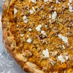 Buffalo chicken pizza topped with sauce and ranch dressing.