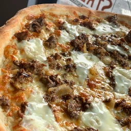 Cheesesteak pizza with beef, onions, and melted cheese.