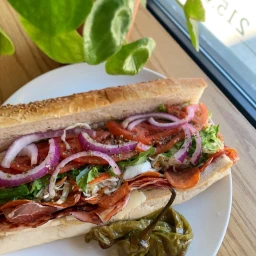 Italian hoagie with meats, lettuce, tomatoes, and onions.